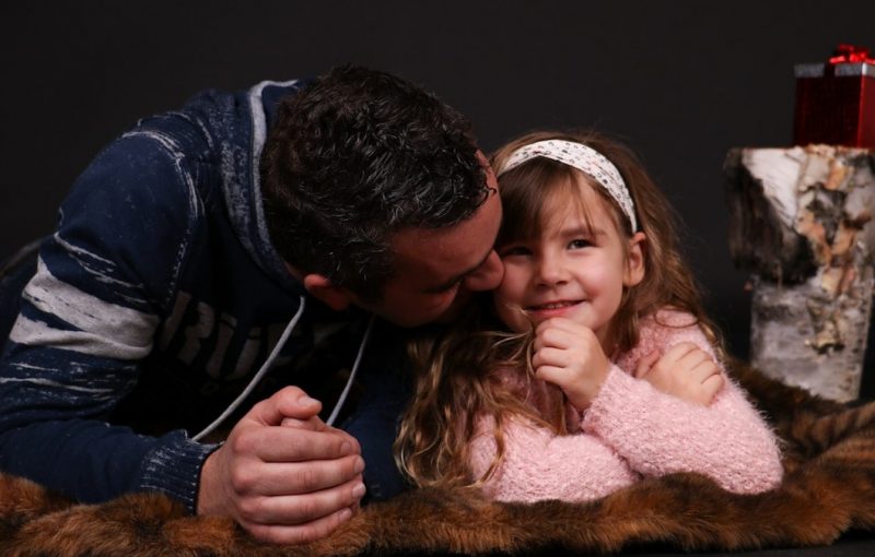 A man kissing a little girl on the cheek