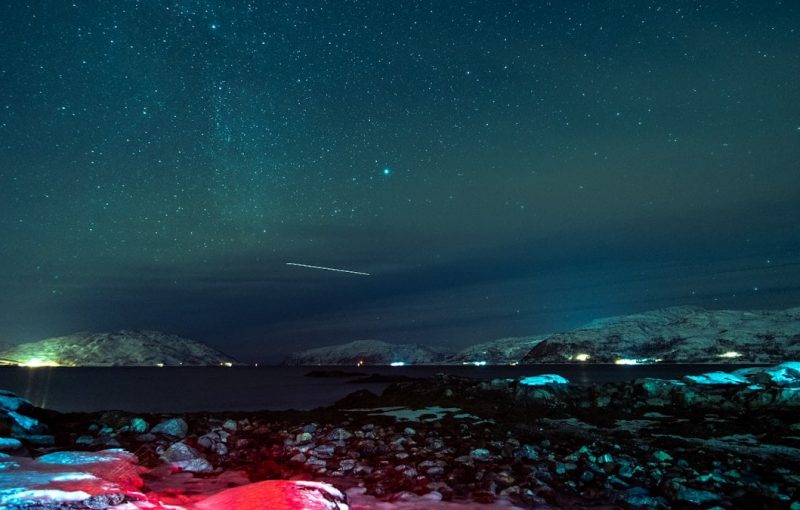 a night sky with stars and a bright red tent in the foreground